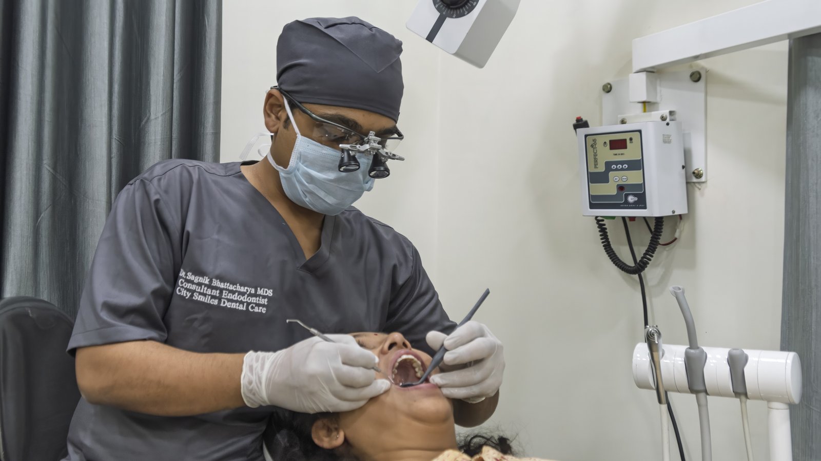 Dr. Sagnik Bhattacharya, Consultant Endodontist at City Smile Dental Care, performing a root canal procedure with magnification loupes